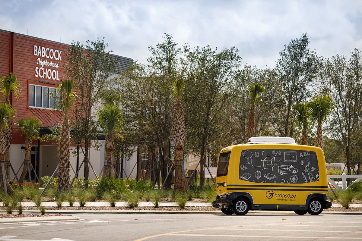 Yellow autonomous shuttle outside Babcock Neighborhood School