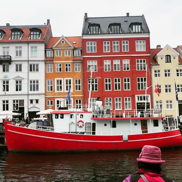 A red boat moored in front of colorful waterfront houses.